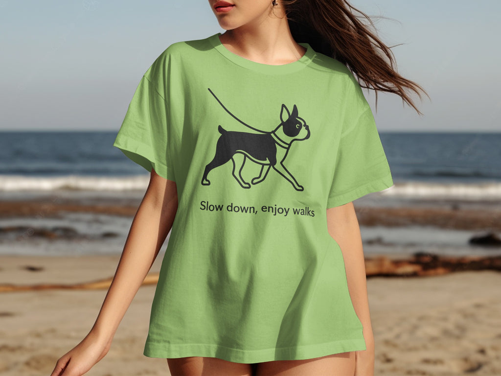 Light green t-shirt with black graphic of dog on leash and text "Slow down, enjoy walks".