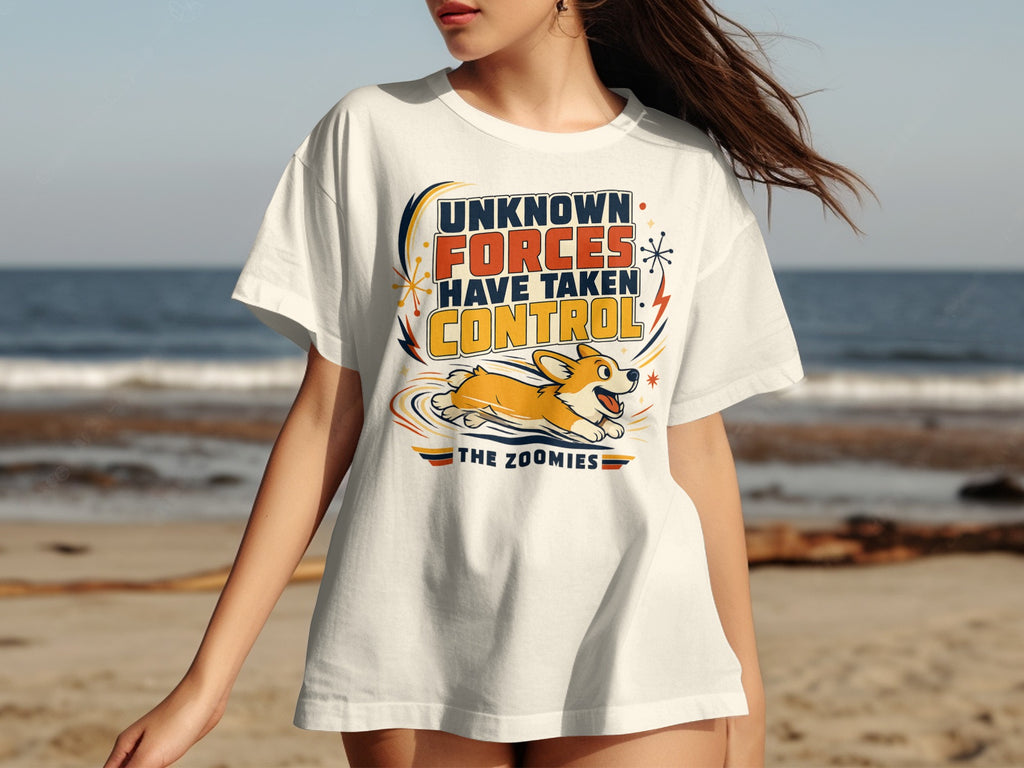 White t-shirt with graphic "UNKNOWN FORCES HAVE TAKEN CONTROL THE ZOOMIES" and a corgi.