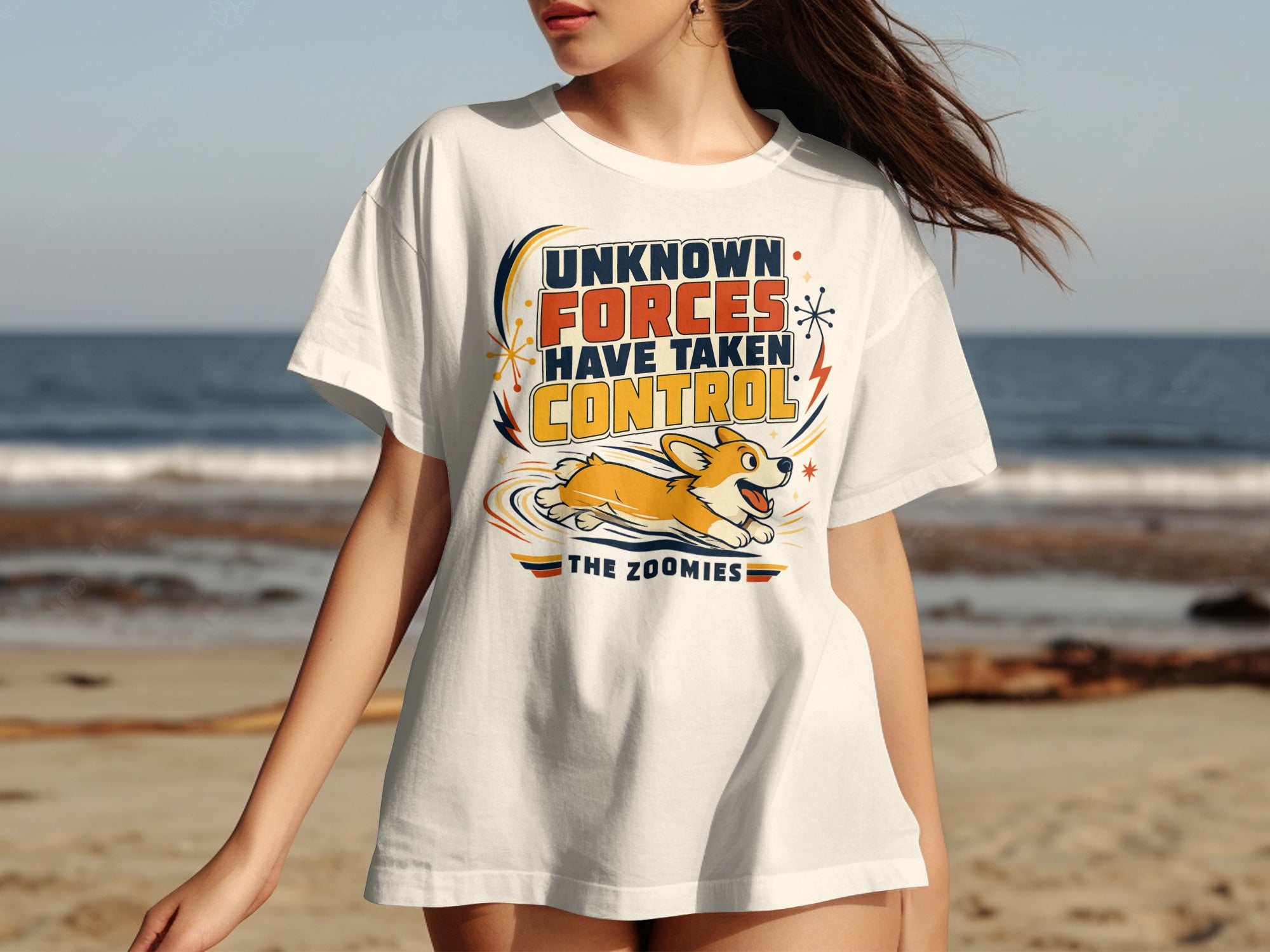 White t-shirt with graphic "UNKNOWN FORCES HAVE TAKEN CONTROL THE ZOOMIES" and a corgi.