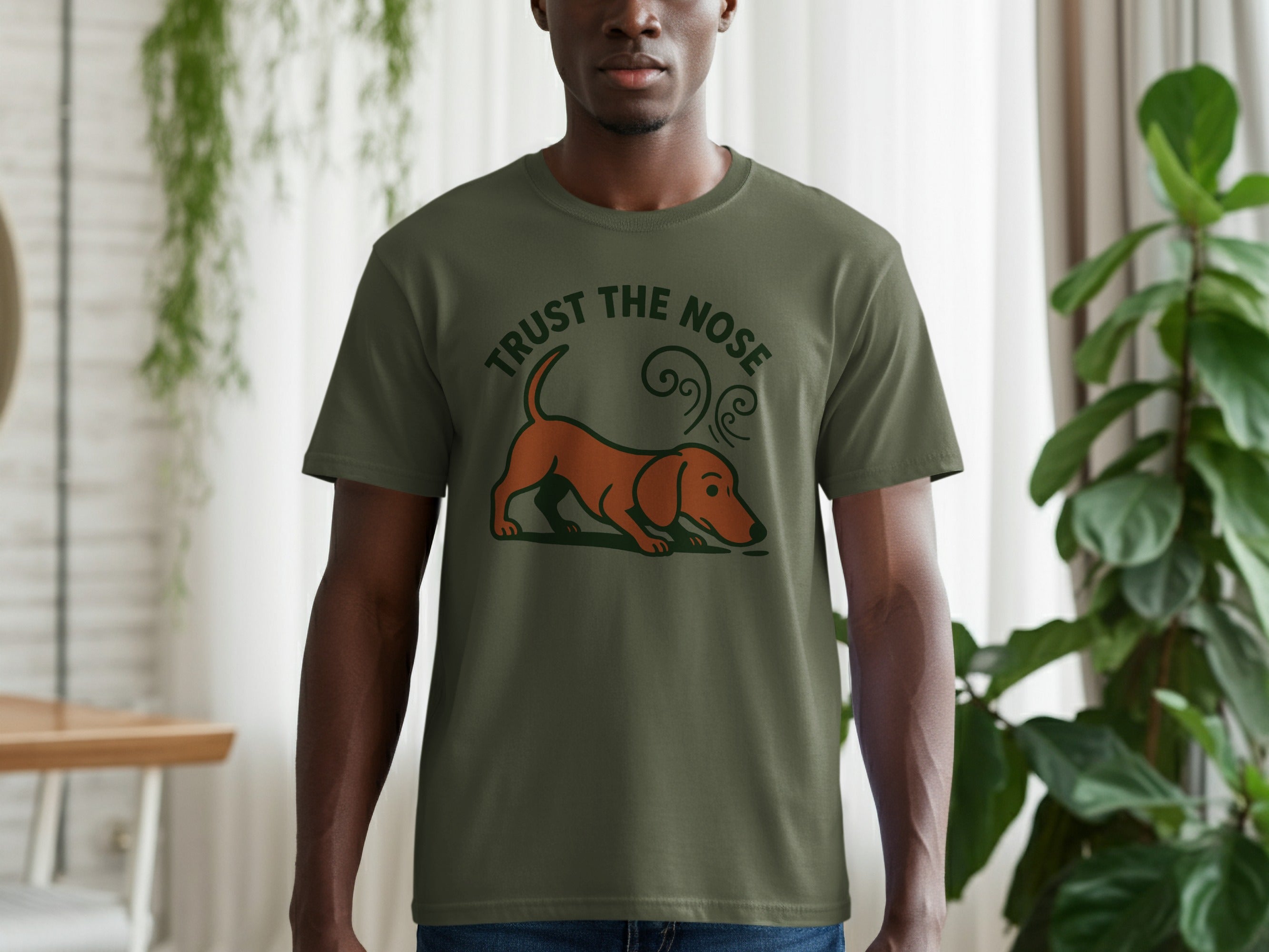 Olive t-shirt with a graphic of a brown dachshund sniffing and text "TRUST THE NOSE."