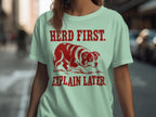 Light green t-shirt with a red dog and text: "Herd First. Explain Later."