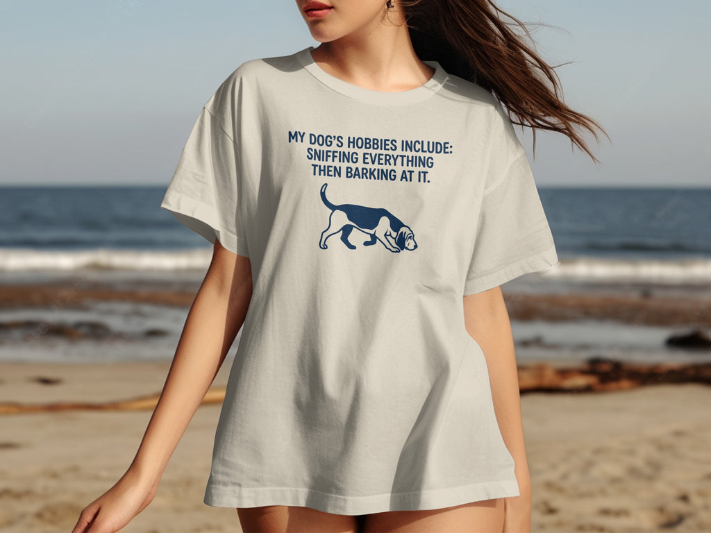 White t-shirt with blue dog graphic and text: "My dog's hobbies include: sniffing everything then barking at it."