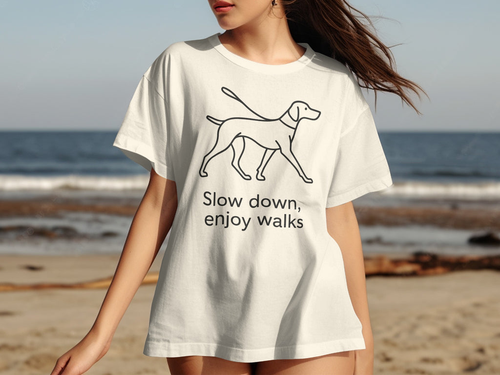 White t-shirt with black line drawing of a dog and text "Slow down, enjoy walks".