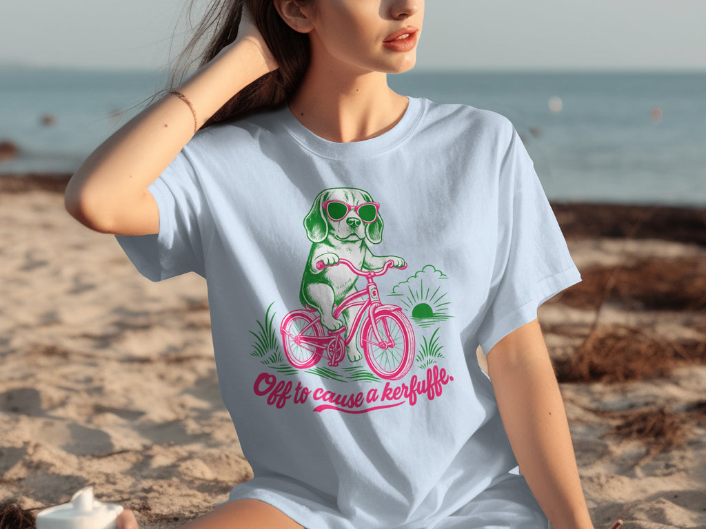 Light blue t-shirt with dog riding a bike and text "Off to cause a kerfuffle".