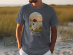 T-shirt graphic: dog sitting by water with "Paws And Reflect" text.