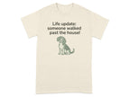 Beige t-shirt with dog graphic and text "Life update: someone walked past the house!"