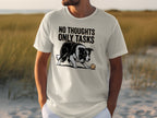 White t-shirt with black dog and ball, text "NO THOUGHTS ONLY TASKS".