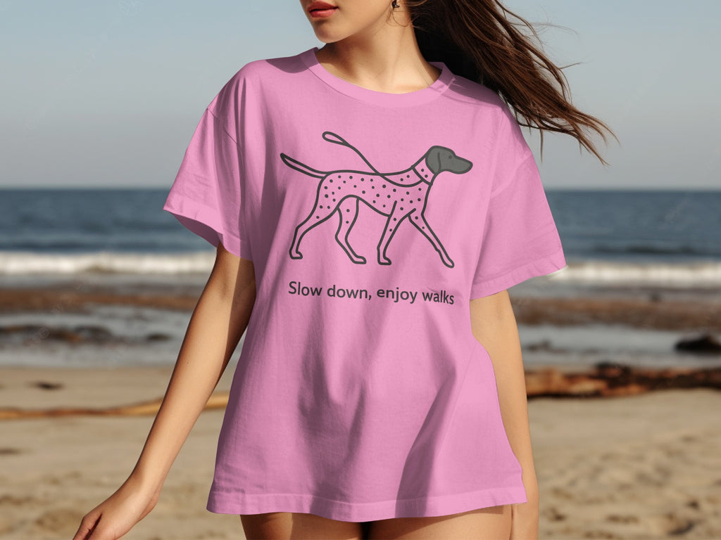 Pink t-shirt with a black line drawing of a spotted dog and text "Slow down, enjoy walks".