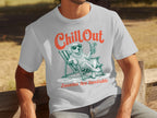 Man in white t-shirt with graphic of dog in sunglasses relaxing with drink.