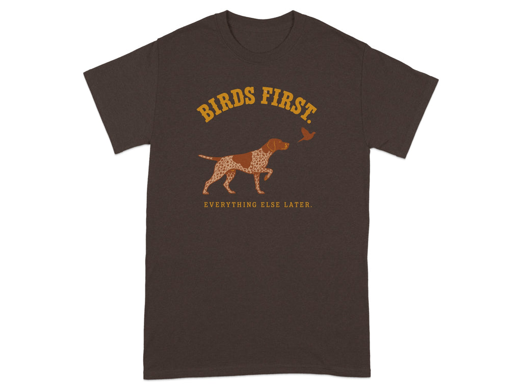 Brown t-shirt with "BIRDS FIRST" and a hunting dog chasing a bird.