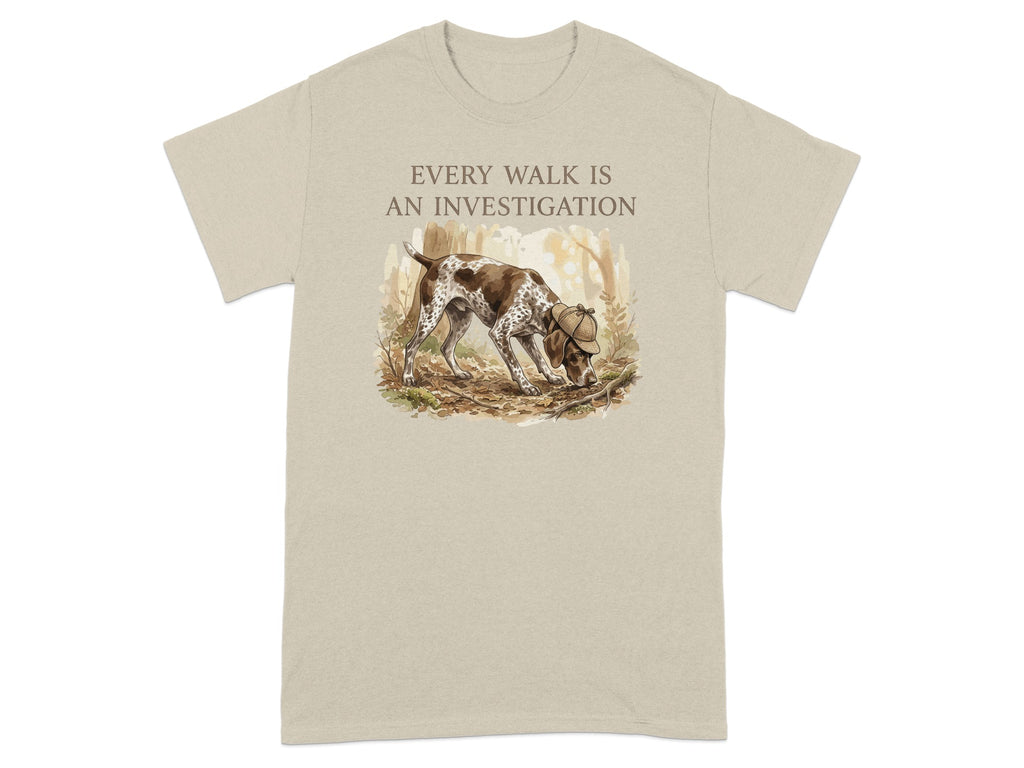 Beige t-shirt with a German Shorthaired Pointer sniffing the ground in a forest.