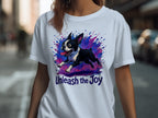 White t-shirt with distressed illustration of a running Boston terrier and text "Unleash the Joy".