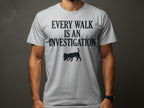 White t-shirt with black text "EVERY WALK IS AN INVESTIGATION" and a dog silhouette.