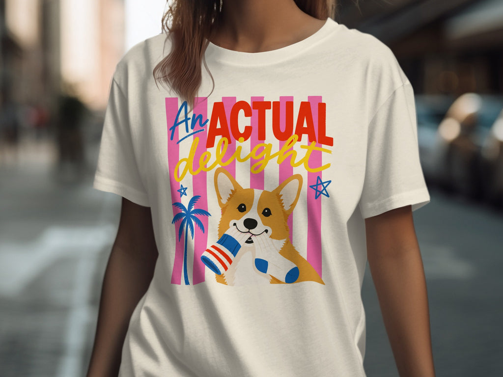 Corgi wearing socks and holding a hot dog on a t-shirt with "An Actual Delight" text.