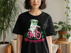 Black t-shirt with a pug wearing sunglasses riding a pink bicycle with text.