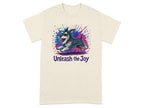 Cream t-shirt features a schnauzer running with paint splatters and "Unleash the Joy" text.