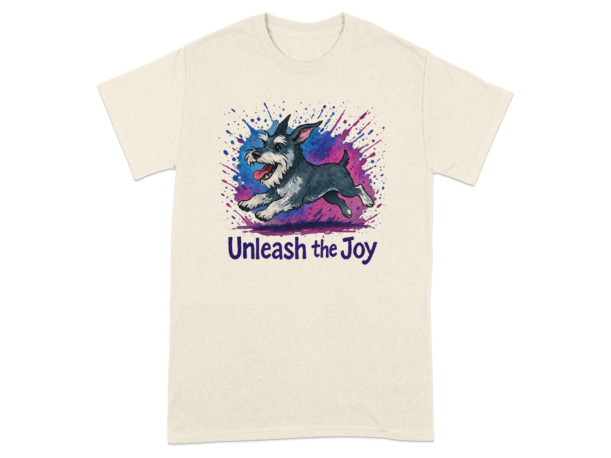 Cream t-shirt features a schnauzer running with paint splatters and "Unleash the Joy" text.