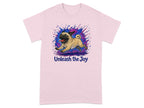 Pink t-shirt with a happy pug running, surrounded by blue and pink paint splatters. Text says "Unleash the Joy".