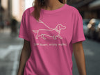 Pink t-shirt with white outline of a dachshund on a leash and text.