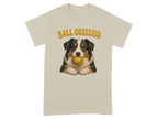 Beige t-shirt with illustration of an Australian Shepherd holding a yellow ball.