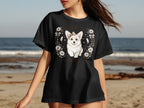 Black t-shirt with a white corgi wearing a bow on its head and text.