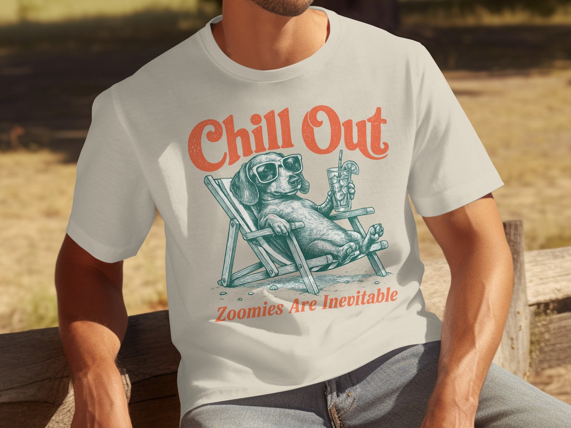 Cream t-shirt with graphic of a dachshund in a lounge chair, "Chill Out" and "Zoomies Are Inevitable."