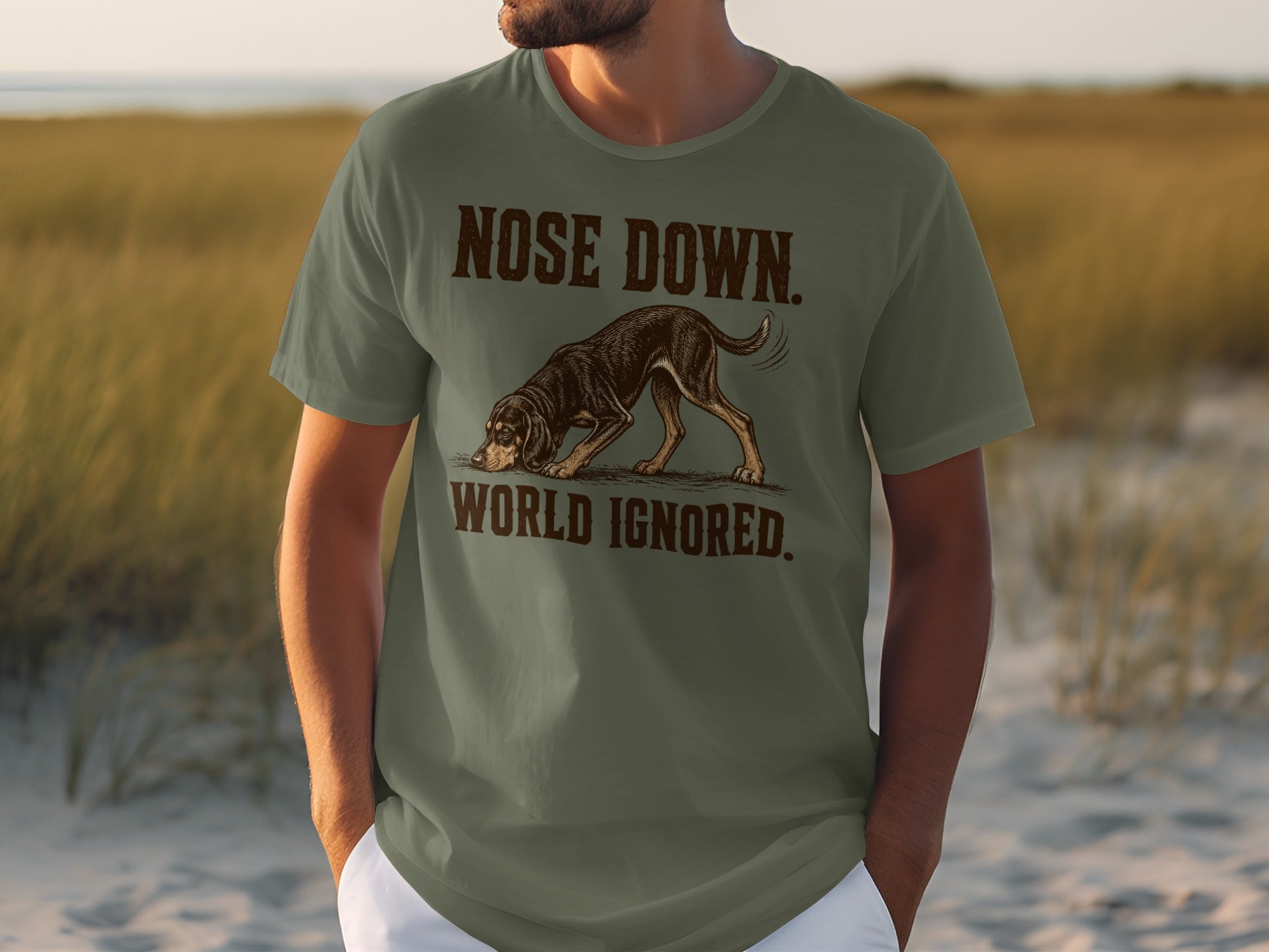 Olive green t-shirt with a graphic of a dog with text "NOSE DOWN. WORLD IGNORED."