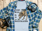 Light blue t-shirt with "Every walk is an investigation" text and dog graphic.