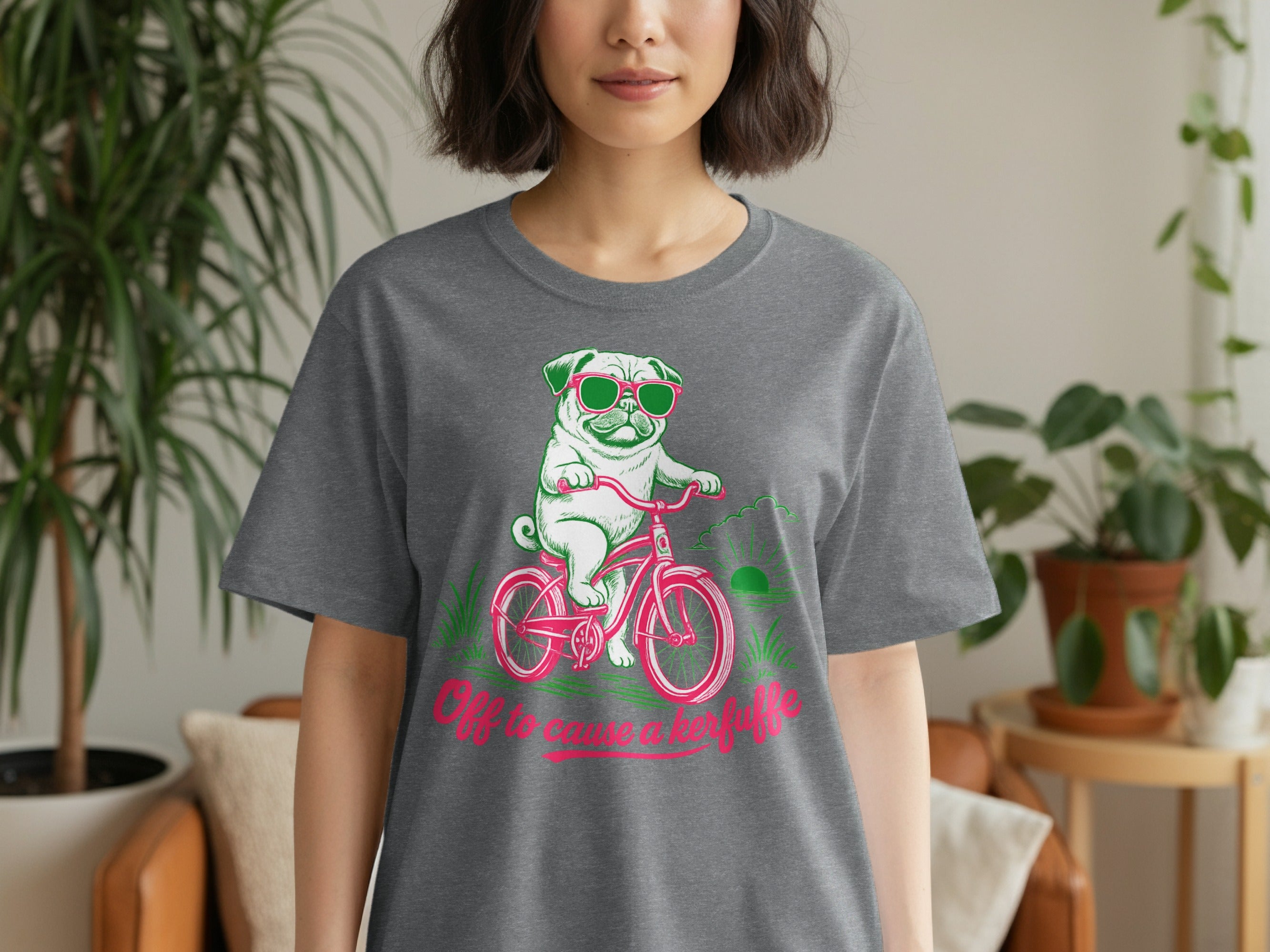 T-shirt with pug in sunglasses riding a pink bicycle, text reads "Off to cause a kerfuffle".
