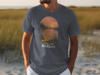 Shirt graphic of a dog looking at a sunset over a lake with text "Paws And Reflect".