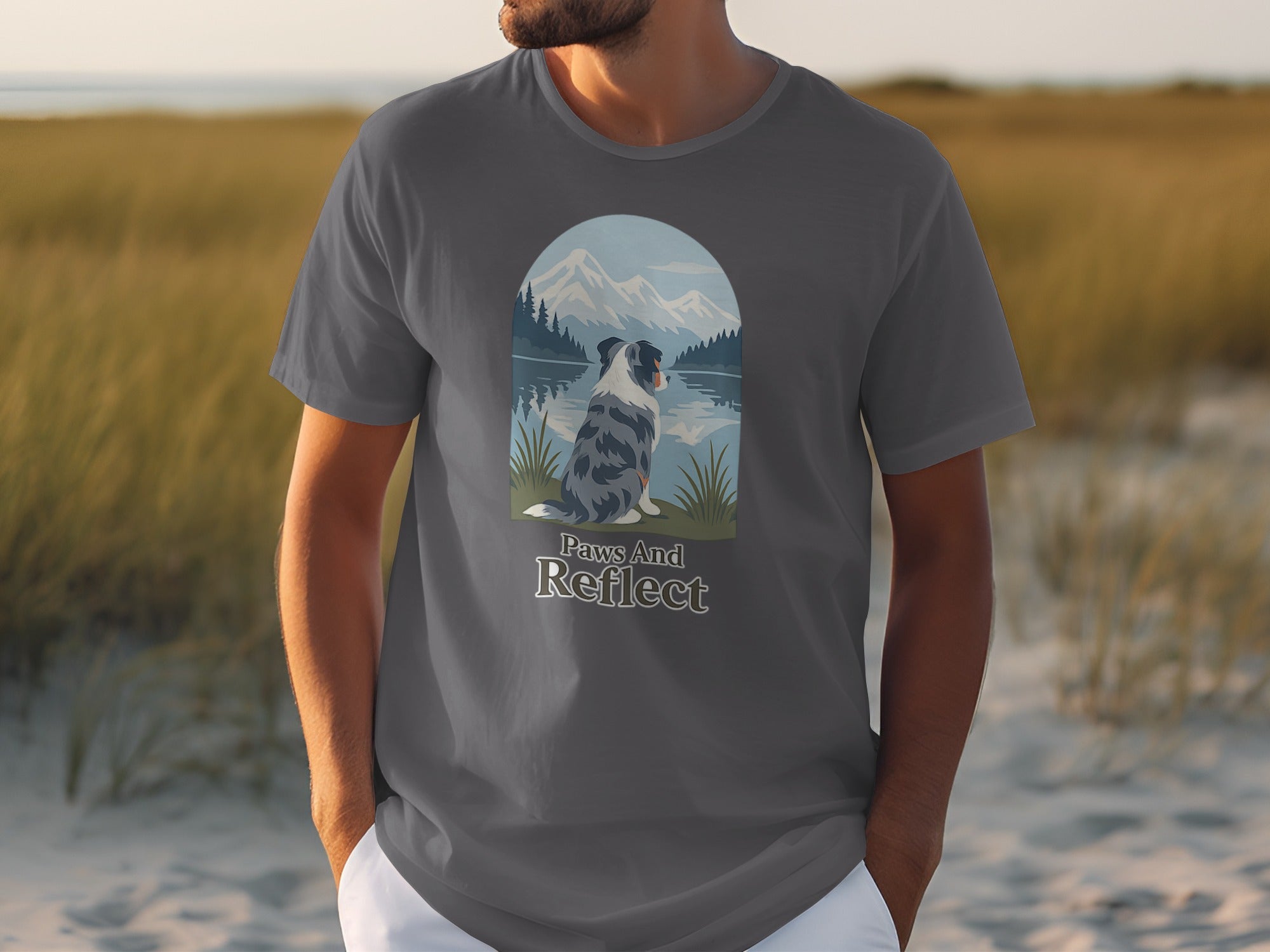 Gray t-shirt with a dog looking at mountains by a lake, text "Paws And Reflect".