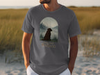 Dark brown dog sitting by water with text "Paws And Reflect" on gray t-shirt.