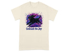 Cream t-shirt with black dog running through colorful paint splatters and text "Unleash the Joy".