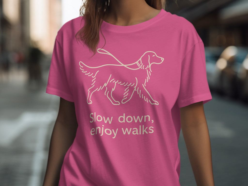 Pink t-shirt with a line drawing of a dog and the text "Slow down, enjoy walks."
