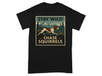 Black t-shirt with graphic of dog chasing squirrel, in a mountain landscape, with text "STAY WILD CHASE SQUIRRELS".