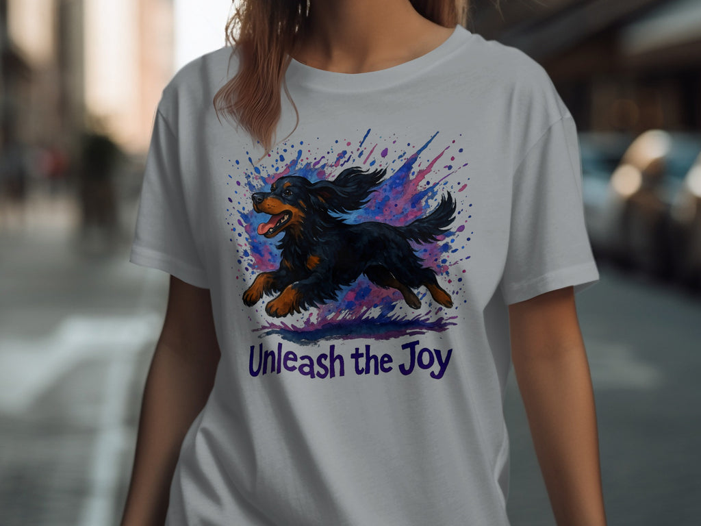 T-shirt with a black dog jumping through colorful splatters and "Unleash the Joy" text.