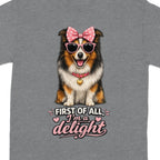 T-shirt with happy dog wearing pink bow, sunglasses, and "First of all, I'm a delight" text.