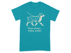 Teal t-shirt with a line drawing of a spotted dog on a leash and the text "Slow down, enjoy walks".