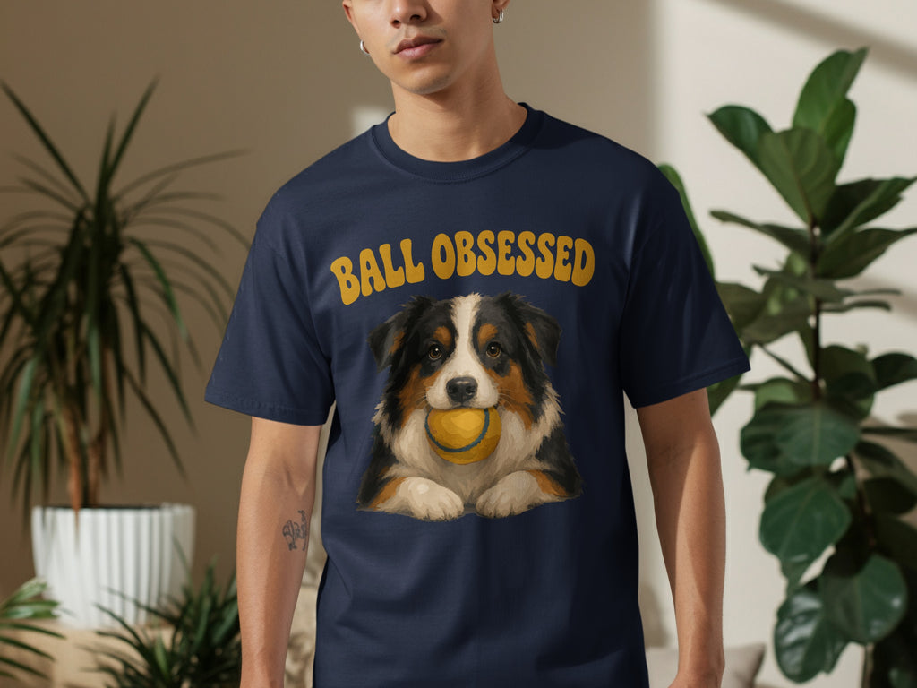 Man wearing navy t-shirt with "BALL OBSESSED" and dog holding a ball.