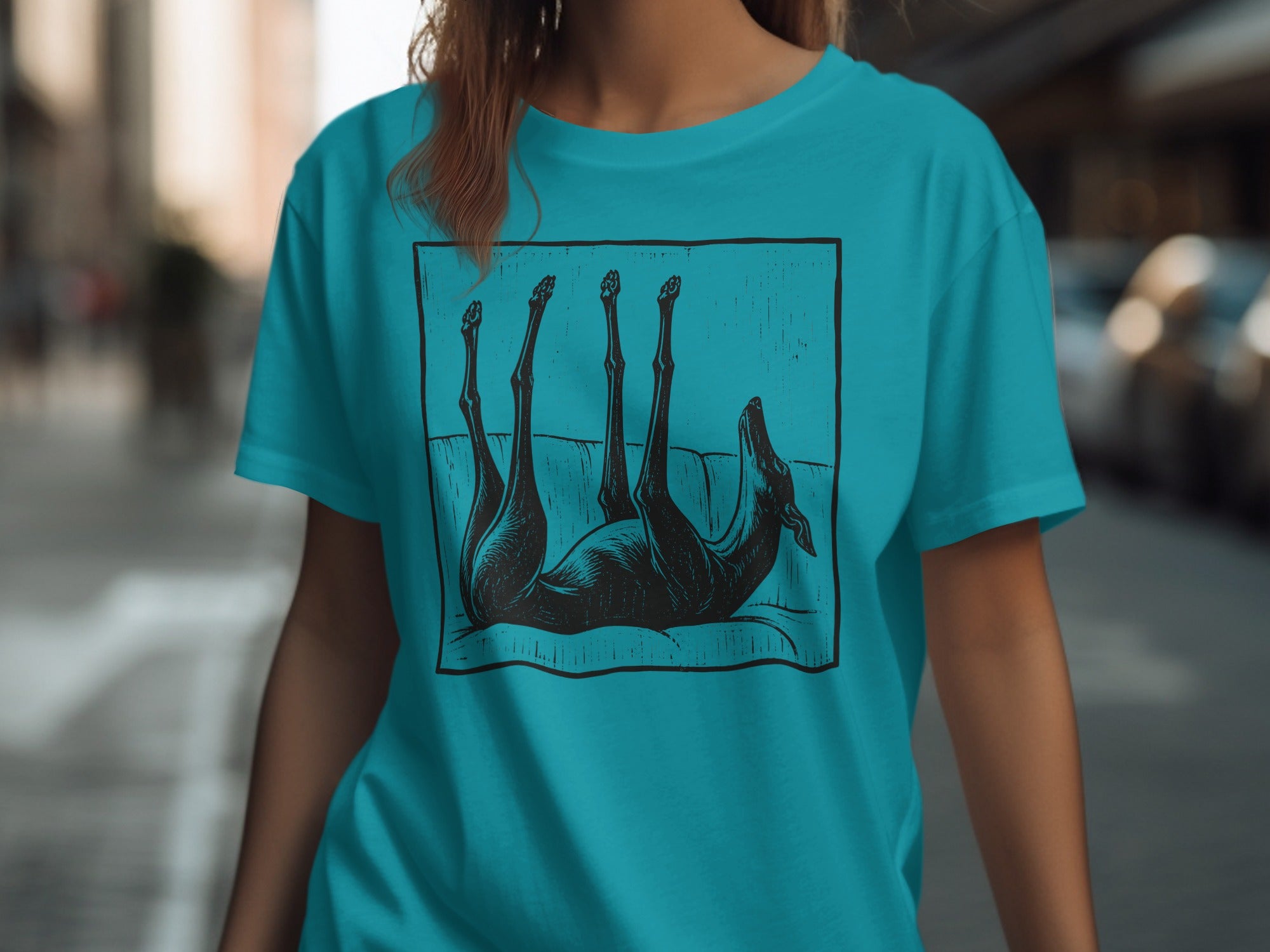 Teal t-shirt with a black graphic of a dog upside down on a couch.