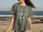 Green t-shirt with a dog, moon, butterflies, and flowers graphic.