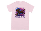 Pink t-shirt with a brown dog running through a colorful paint splatter and text "Unleash the Joy".