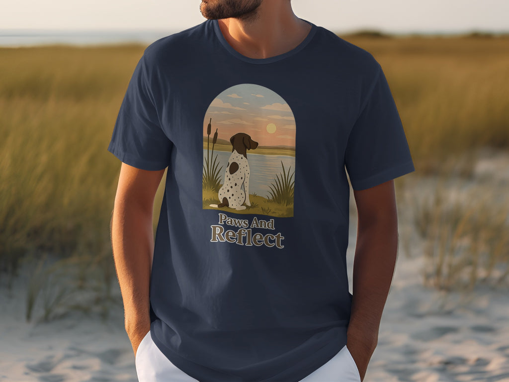 T-shirt with a spotted dog gazing at a sunset over water, text "Paws And Reflect".
