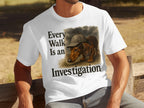 White t-shirt with a dachshund wearing a hat and text "Every Walk Is an Investigation".