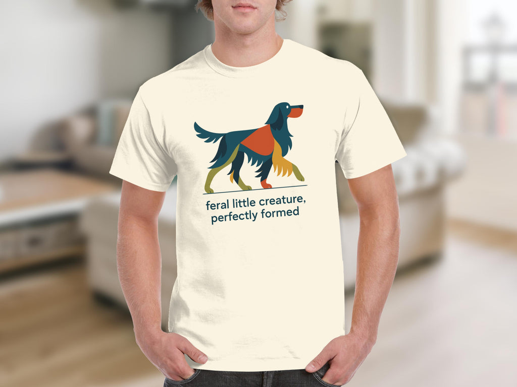 Cream t-shirt with abstract colorful dog and text: feral little creature, perfectly formed.