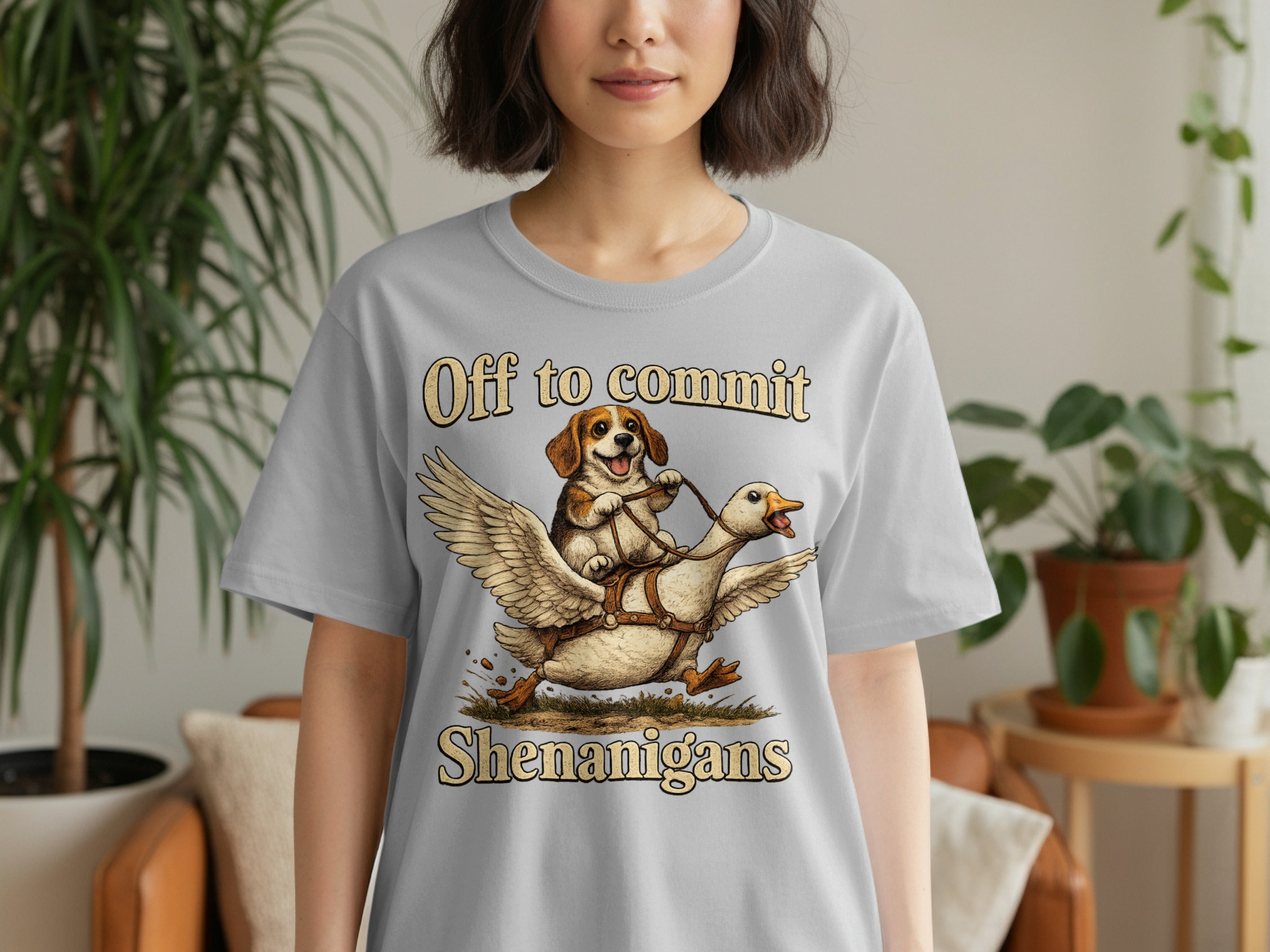 T-shirt with dog riding a winged goose and text "Off to commit Shenanigans".