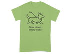 Light green t-shirt with a line drawing of a dog on a leash and the text "Slow down, enjoy walks".