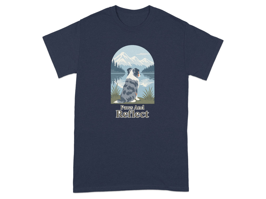 Blue and gray dog sitting by a lake with mountains and forest behind.