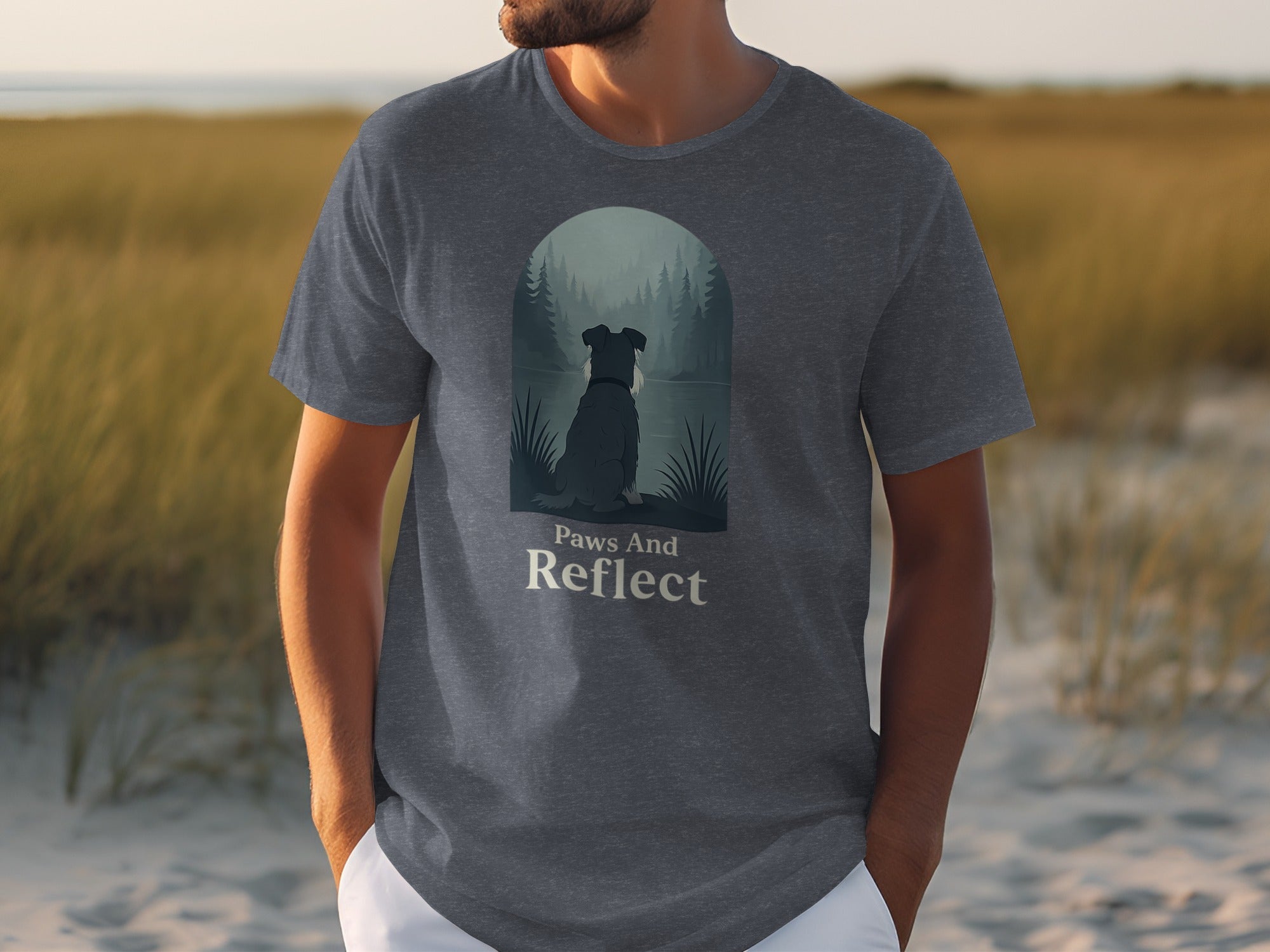 Grey t-shirt with a dog looking out at a misty forest and lake, text reads "Paws And Reflect".