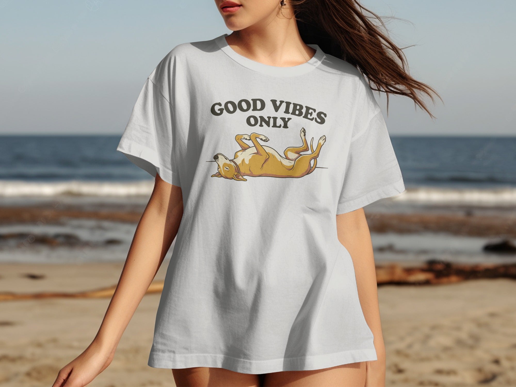 White t-shirt with "GOOD VIBES ONLY" and dog graphic on beach background.